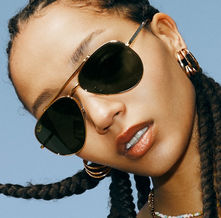 A woman in front of a blue sky wearing ray-ban sunglasses